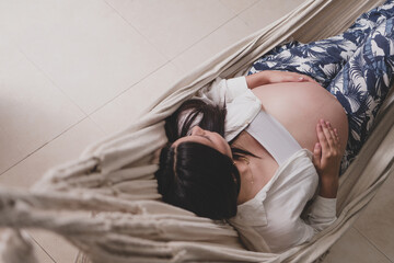 Pregnant woman happy seeing sunset relax awaiting lying in a hammock