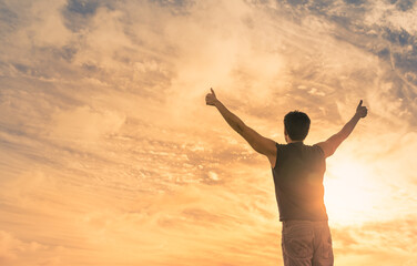 Fototapeta na wymiar young man with arms up feeling inspired hopeful looking out to the sunrise 