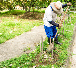 persona trabajadora en jard&iacute;n con pala y botas limpiando para sembrar plantas en jardin