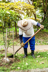 persona trabajadora en jardín con pala y botas limpiando para sembrar plantas en jardin