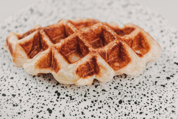 Close up small piece of homemade waffle on white dots dish.