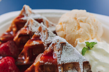 Dessert set of ice-cream waffle with cherries served on blue table.