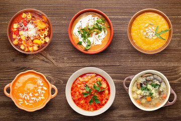 Set of tasty soups on wooden background, top view