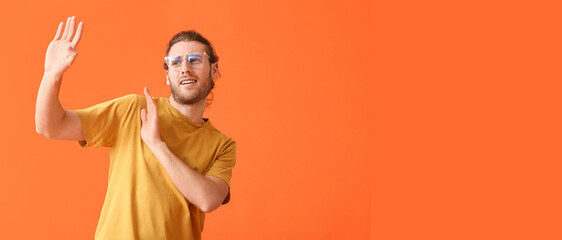 Young man wearing eyeglasses and rejecting something on orange background with space for text