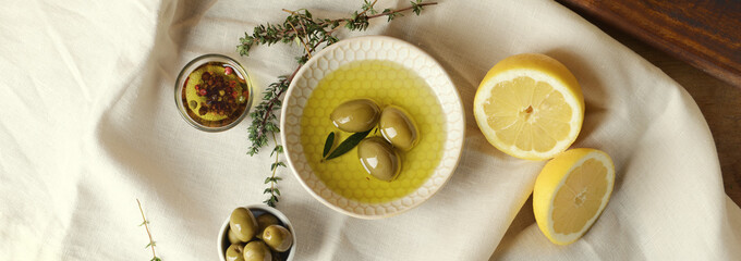 Tasty olive oil with lemon and herbs on table, top view