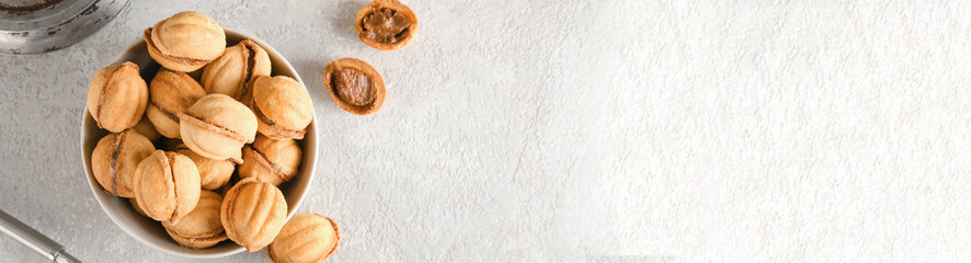 Bowl of walnut shaped cookies with boiled condensed milk on grunge background with space for text