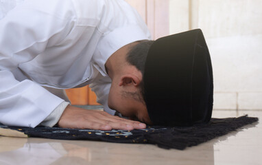 Portrait of a Muslim man praying in an act of prostration called Sajdah or prostration. Side view...