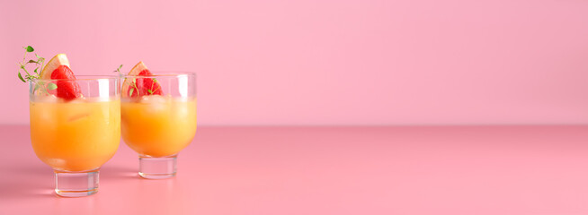 Glasses of fresh grapefruit juice on pink background with space for text