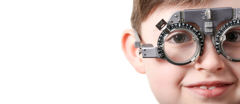 Little boy with trial frame undergoing eye test on white background with space for text, closeup