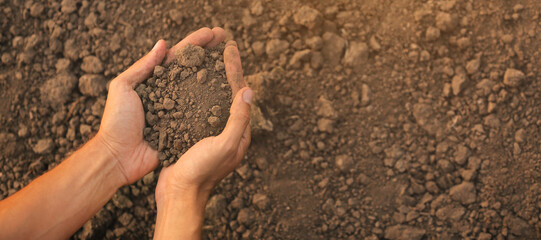 Hands of farmer with heap of soil in field. Banner for design