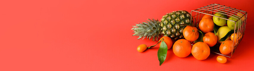 Overturned basket with many juicy fruits on red background with space for text