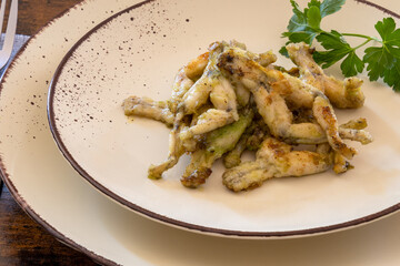 frog legs cooked with parsley on a plate, french cuisine