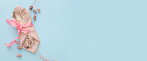 Stylish cutlery and napkin on light blue background with space for text