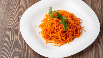 Delicious and spicy carrot spaghetti. Delicious spicy juicy bright Korean carrots on a wooden background. Asian cuisine