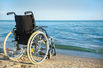 Obraz premium Empty wheelchair near sea on summer day