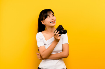 Obraz premium Photographer girl taking pictures. Isolated model on yellow background. with copy space
