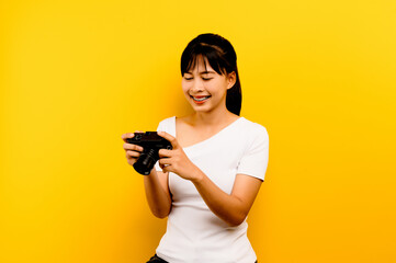 Photographer girl taking pictures. Isolated model on yellow background. with copy space