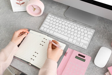 Woman making notes in notebook on table, closeup