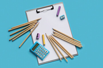 Clipboard with blank paper sheet, sharpeners, erasers and colorful pencils on blue background