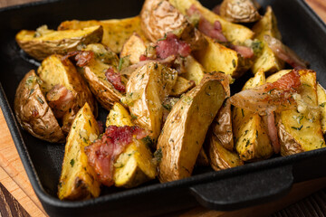 Delicious Fried Potato Bratkartoffeln With Bacon and Onion close up in the black plate on the table.