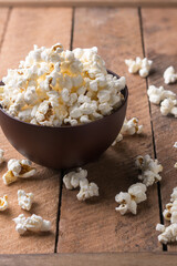 popcorn in a brown cup with scattered on a wooden table top, delicious, low-fat, healthy snack, taken in shallow depth of field