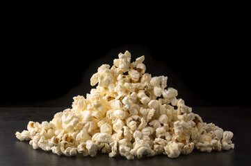 pile of popcorn on black background, delicious, low-fat, healthy snack, closeup