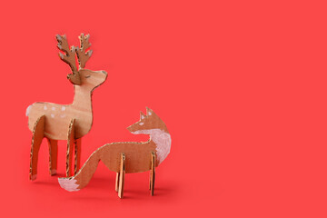 Handmade cardboard reindeer and fox on red background