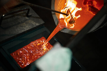 Pouring liquid silver into casting form with metal tool