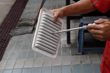Mechanic blowing air on the car air filter
