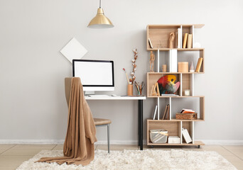 Interior of light office with workplace, shelving unit and paint brushes