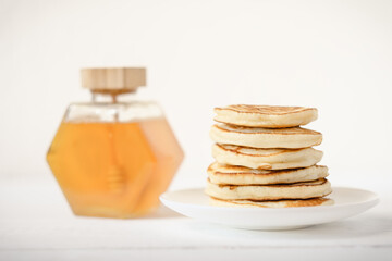 fresh home baked pancakes in a pile with honey in a glass bottle. home baking, cooking for family