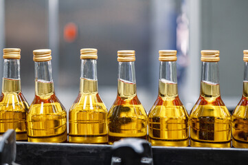 Bottles of golden alcohol with caps transported by conveyor