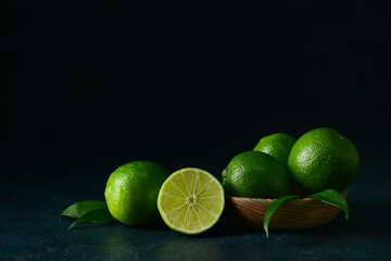 Bowl of fresh ripe limes on dark background