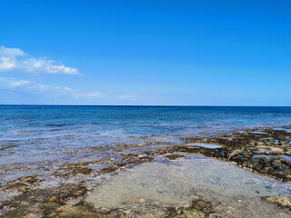  The coast of the Mediterranean Sea, long frozen lava, in the recesses of which there is sea water against a blue sky .