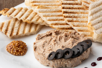 Liver meat pate spread with grilled white bread on a wooden background, breakfast, close-up, no people, selective focus, pasticcio, pastete