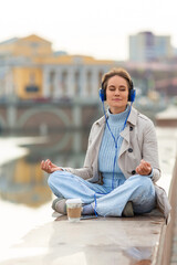 35 years old woman meditates - she sitting in headphones and listens to relaxing music during a...