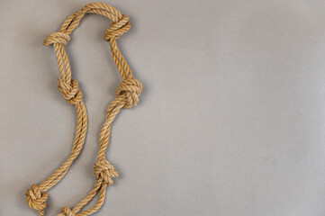 The yellow rope against the gray background. Ship's rope with simple knots.
