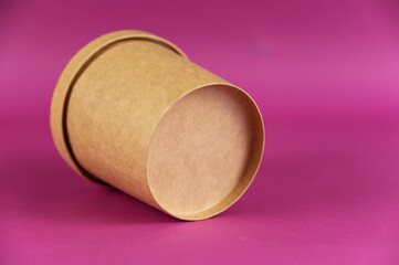 Food to take away. Closed cylindrical paper container with lid opposite colored background. Brown food container for soup, ice cream, noodles or other food.