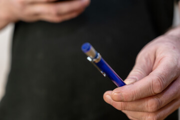 A man's hand holds a blue pen. Middle section of man with ballpoint pen in hand.
