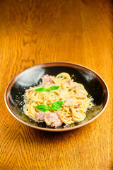 Italian recipe Pasta tortilloni with green pea, mint leaves, cheece, smoked bacon and cheese. Top view, blue background