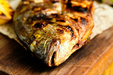 Big fish dorado with lemon and sauce on wooden table in luxury restaurant