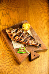 Big fish dorado with lemon and sauce on wooden table in luxury restaurant