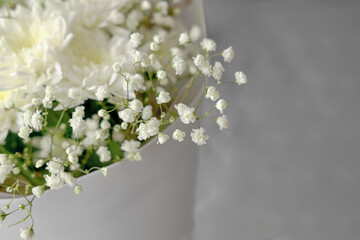 bouquet of white chrysanthemums and gypsophila wrapped in craft paper. delicate bouquet of white flowers. Spring bouquet of white chrysanthemums close-up.