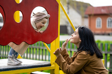 Child education concept. Mom and daughter are playing on the playground.