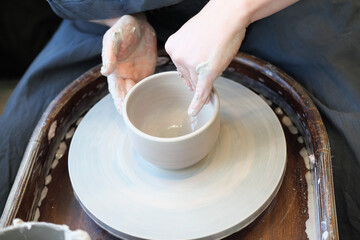 Cropped image of unrecognizable pottery woman working with pottery wheel
