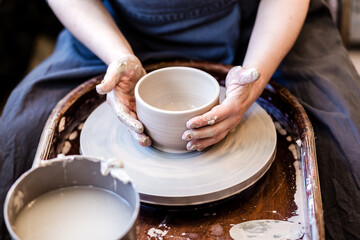 Cropped image of unrecognizable pottery woman working with pottery wheel