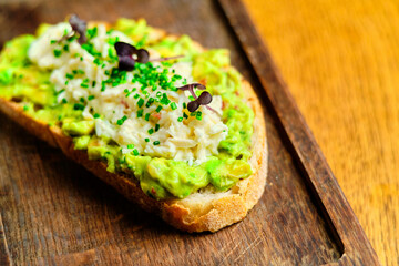 Whole grain bread toast with avocado on a wooden board