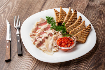 Raw chopped pork lard with meat, a head of garlic and rye bread on a wooden background for copy space. A large chunk of fresh fat.