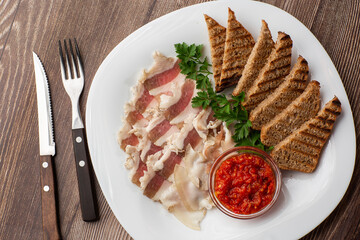 Raw chopped pork lard with meat, a head of garlic and rye bread on a wooden background for copy...