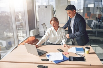 mature businesswoman is showing to colleague her project in laptop. Business relation concept.